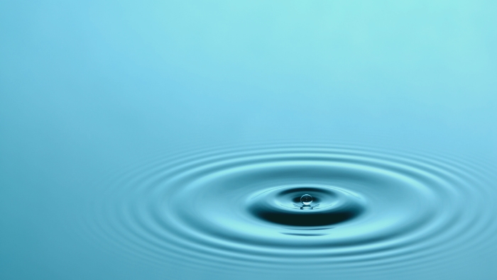 A ripple expanding across calm blue water, representing the impact of holistic care providers in Madison and the interconnected nature of healing.