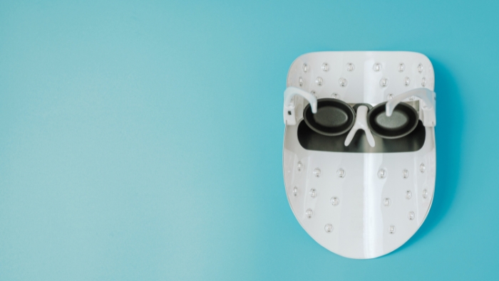 led light therapy White LED light therapy mask with protective goggles against a light blue background.