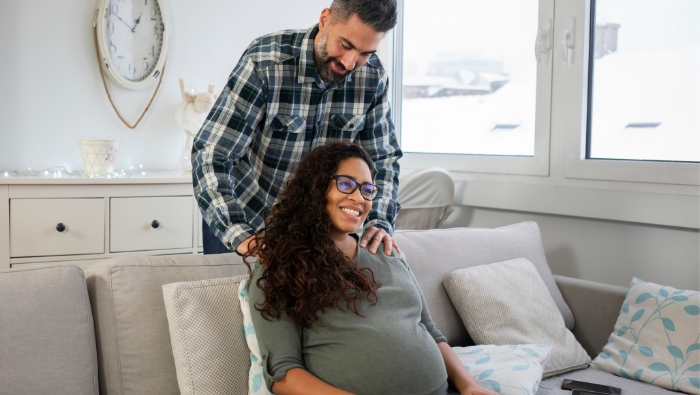 Partner gently massaging pregnant woman’s shoulders at home, illustrating the partner’s role in prenatal massage and supportive touch.